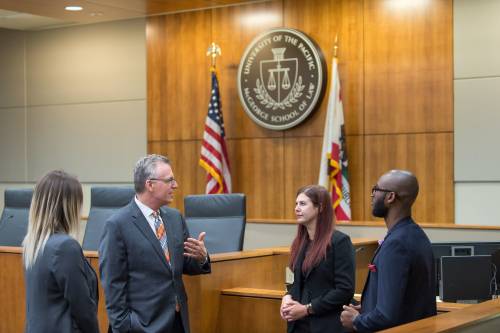 Michael Hunter Schwartz, Dean of McGeorge School of Law, speaking with students in the law school's courtroom.